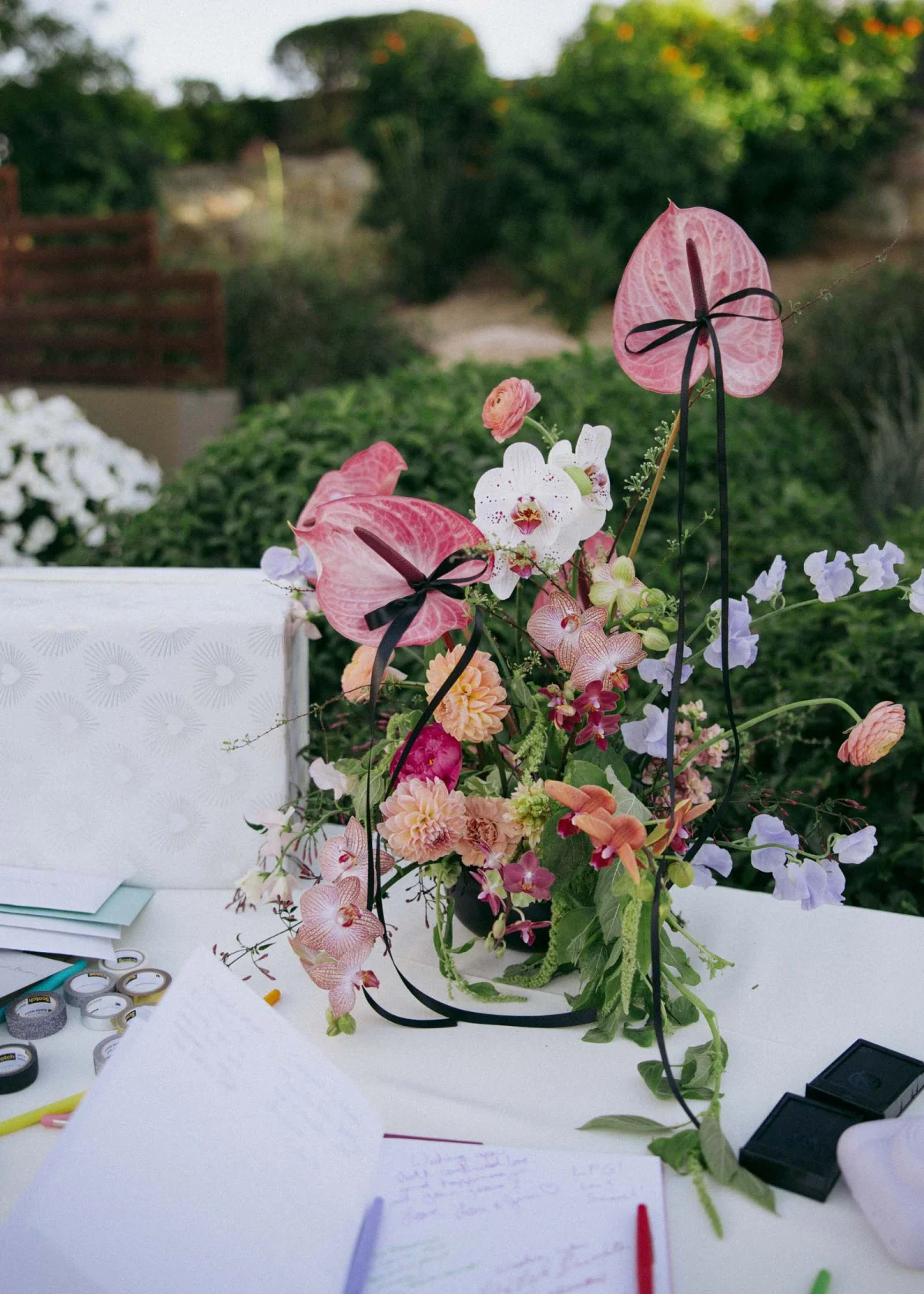Long thin black ribbons tied onto anthurium flowers in a wedding centerpiece