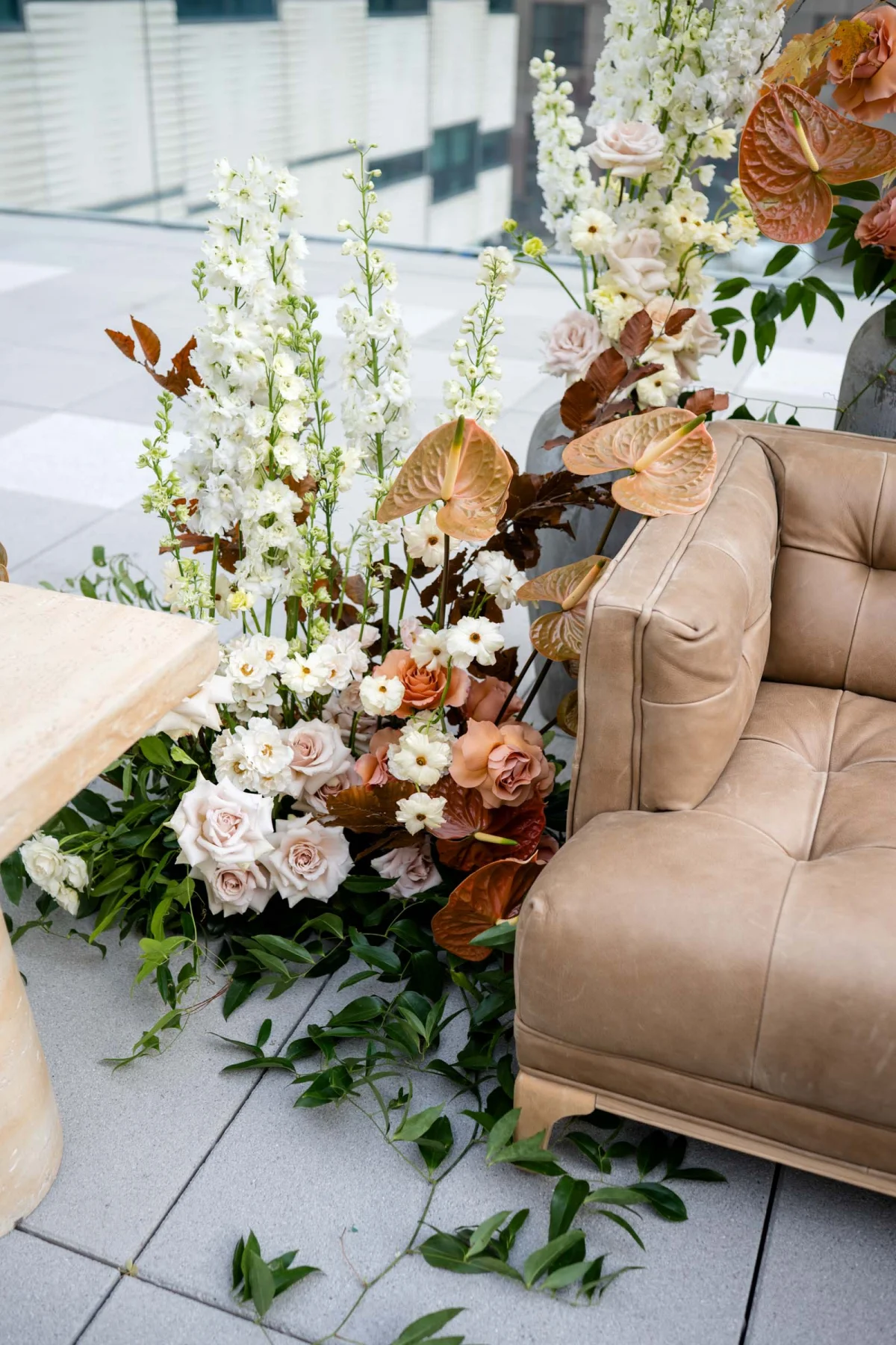 Gorgeous mushroom brown leather sofa surrounded by autumnal flowers with muted colored anthurium for fall wedding lounge ideas