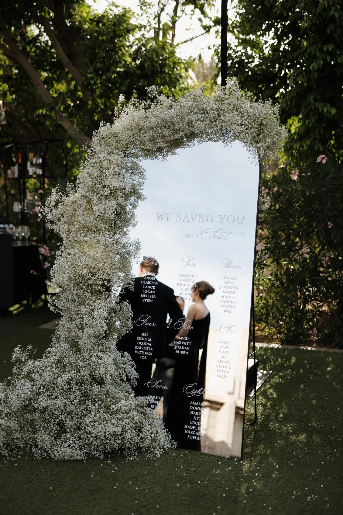 Large mirror seating chart decorated with baby's breath flowers