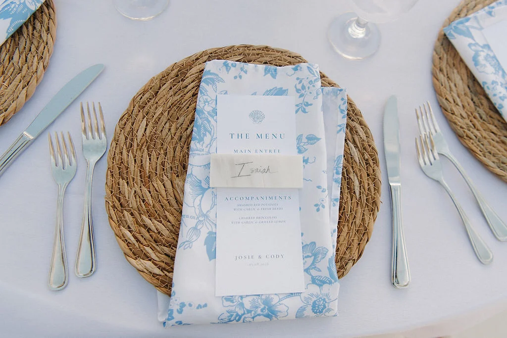 Beach blue floral napkins, menu with seashell illustration, and marble slab place card for elegant coastal place settings