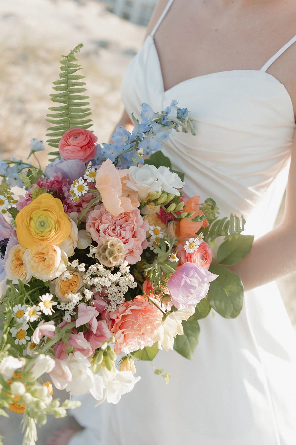 Colorful pastel wedding bouquet with ranunculus, daisies, and roses