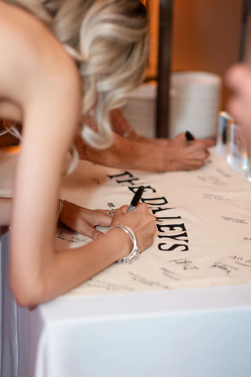 Guests signing unique wedding guest book banner with the couples new last name