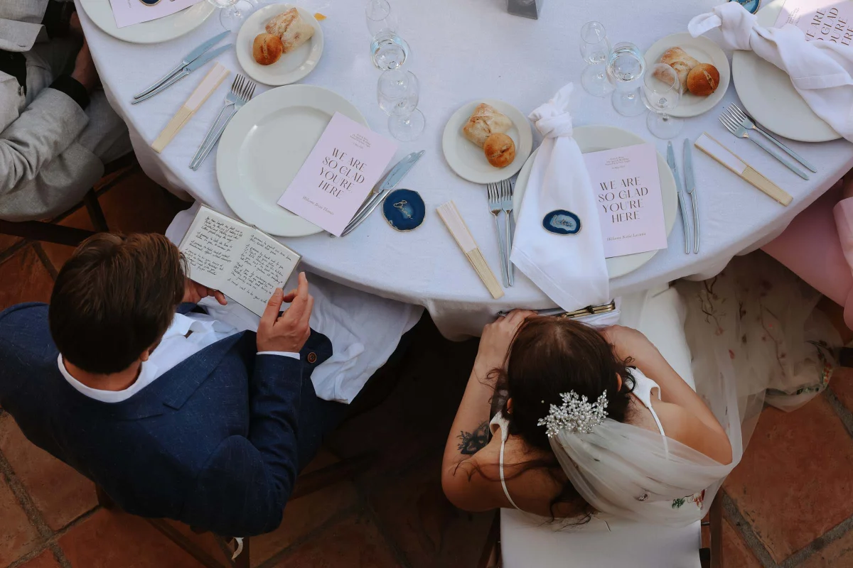 Bride and groom seated at their wedding reception table with their friends