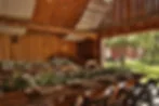 Rustic summer wedding reception in a barn venue with string lights overhead and long wooden tables decorated with greenery