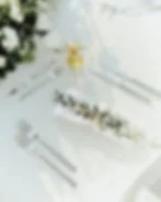 Wedding reception table with elegant napkin folds, place cards, and stacked plates showing creative charger alternatives on a budget