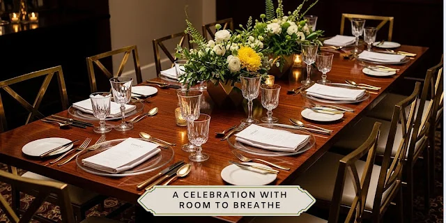 Intimate wedding reception table with warm candlelight, gold chairs, white place settings, crystal glassware, and green-and-white floral centerpieces