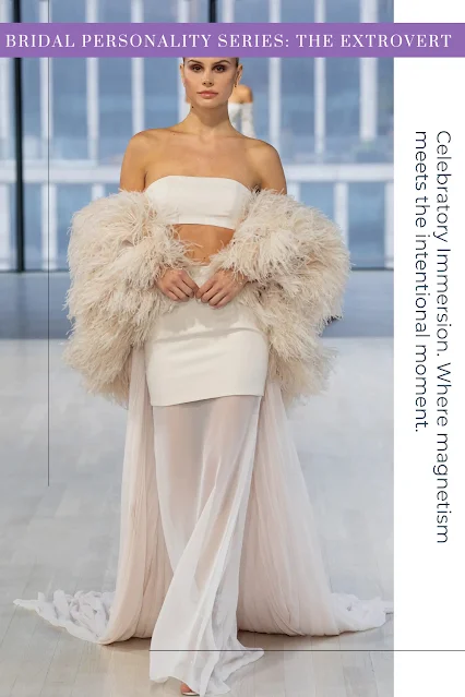 A couture bridal ensemble by Nicole and Felicia featuring a sleek white strapless mini dress, a dramatic oversized beige feather wrap, and a sheer flowing tulle overskirt with a long train.